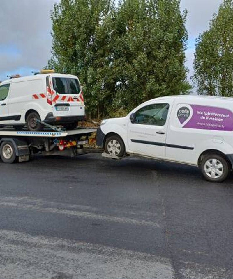 Bestelwagen opgeladen op de takelwagen naast een bestelwagen van een pakketdienst