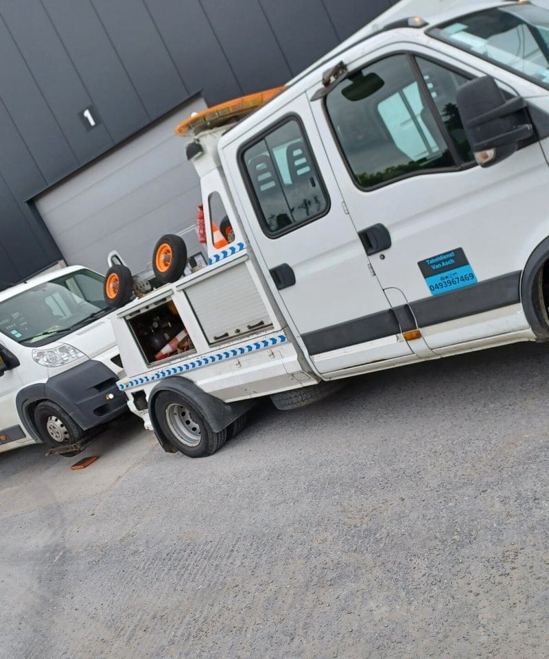 De bijstandswagen van Depannage Van Asch met het telefoonnummer op de flank, voor de eigen loods
