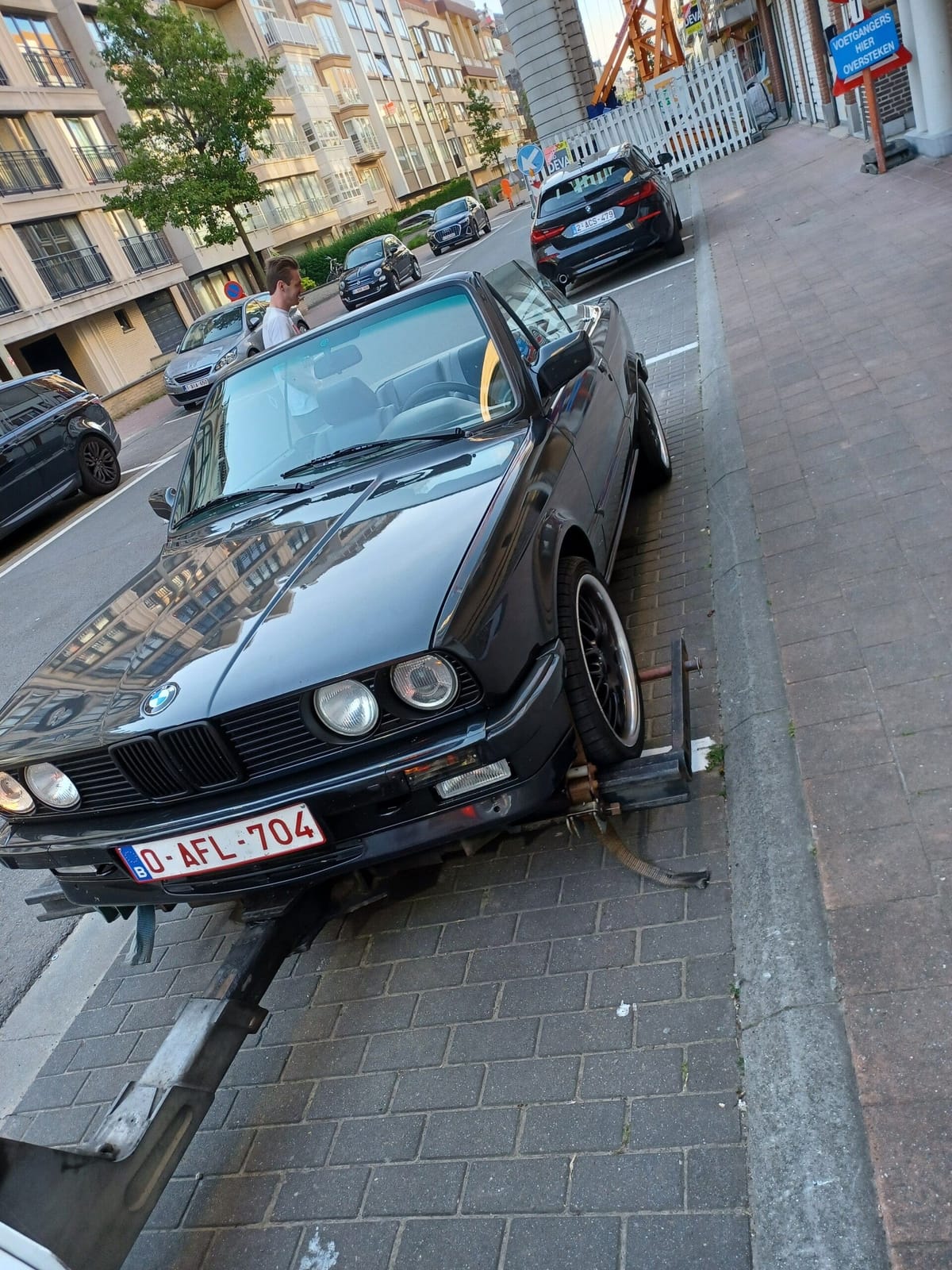Klassieke zwarte cabriolet vastgemaakt op de takelbrug in een stadsstraat