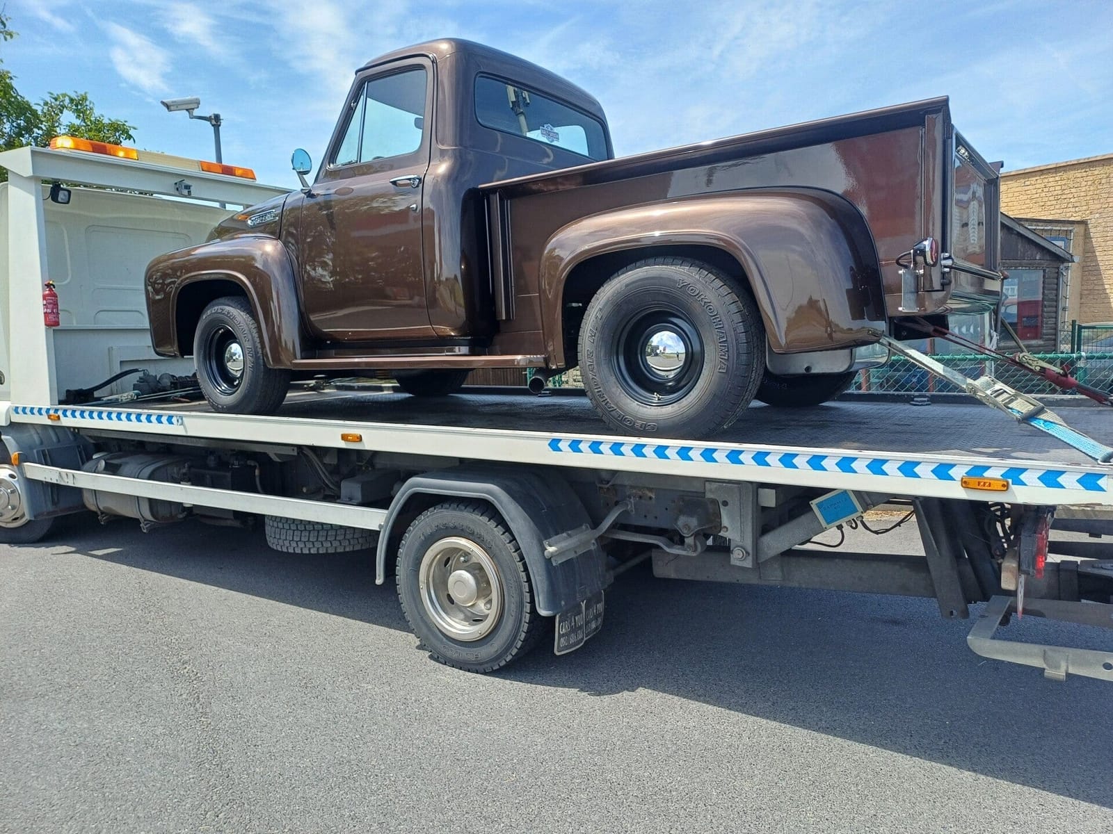 Klassieke pick-up truck vastgezet op de platte laadbak van de takelwagen