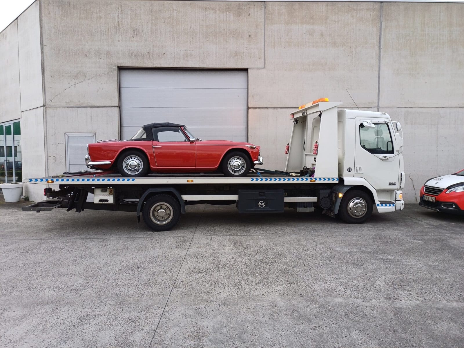 Rode klassieke cabriolet vastgezet op de platte laadbak van de takelwagen