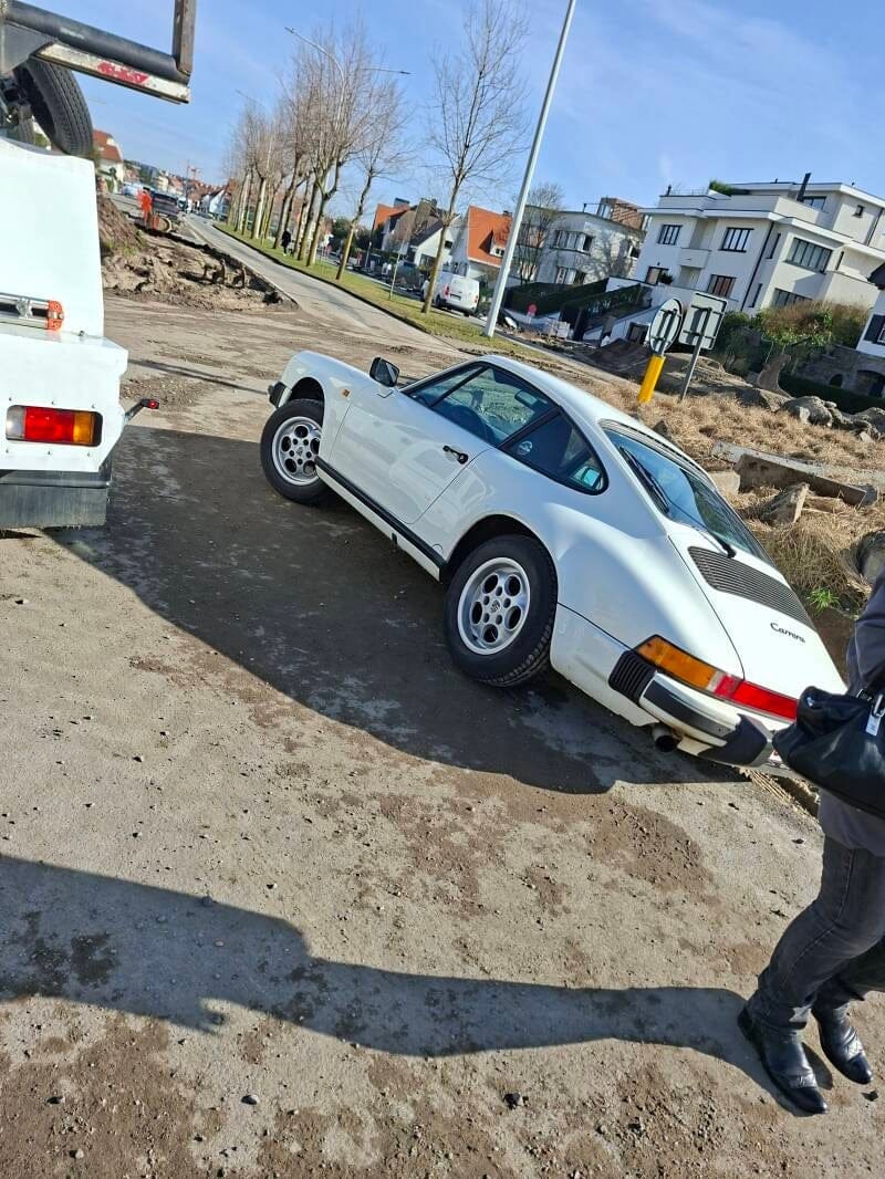 Witte Porsche 911 Carrera naast de takelwagen, klaar om geladen te worden